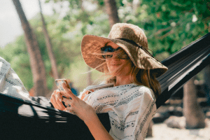 Femme avec chapeau et lunettes de soleil en train de bronzer sur un hamac